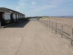 a boardwalk on the beach next to a building at Beachside, Family-friendly, WiFi, 6 berth Caravan 12 in Ingoldmells