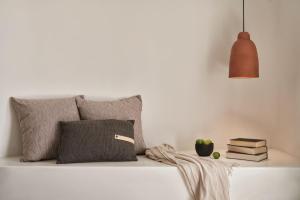 a bed with pillows and a lamp and books at Orama Hotel & Spa in Fira