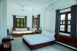 a bedroom with two beds and two windows at Villa 360 in Talpe