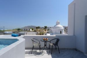 a balcony with a table and chairs and a pool at Ikies Santo Filoxenia Apartments in Karterados