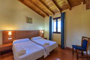 una habitación de hotel con dos camas y una silla en Hotel Ibaigune, en Murueta