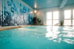 a large swimming pool with blue water in a room at Thalacap Île de Ré - Thalasso & Spa in Ars-en-Ré