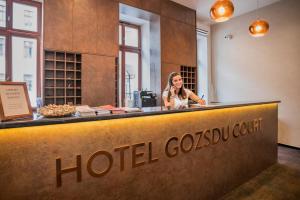 una mujer hablando en un celular detrás de un mostrador de hotel costouri en Hotel Gozsdu Court en Budapest