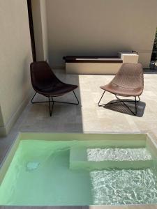 twee stoelen en een zwembad met water in een kamer bij Chiusa Di Carlo Agriturismo in Avola