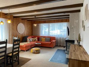 ein Wohnzimmer mit einem orangenen Sofa und einem Tisch in der Unterkunft Immeuble Le Cervin in Les Collons