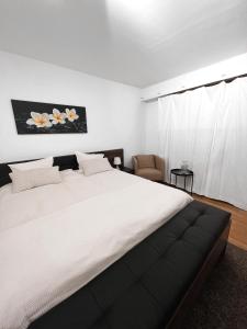 a bedroom with a large white bed and a chair at Eine schöne Wohnung im Herzen von Basel. in Basel