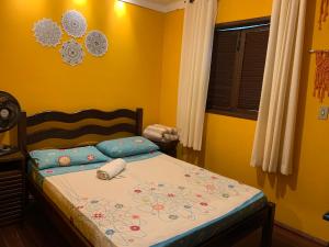 1 dormitorio con 1 cama con pared amarilla en Casa em Lumiar - Barulhinho do Rio, en Lumiar
