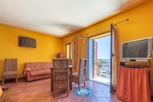 a living room with yellow walls and a television and a couch at Stenopus Greco Casa per AFFITTI TURISTICI in Santa Flavia