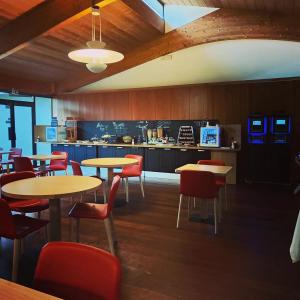 a restaurant with tables and chairs and a kitchen at Hôtel Les Grenettes in Sainte-Marie-de-Ré