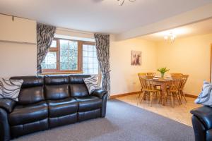 a living room with a leather couch and a table at Yr Wyddfa Cottage Anglesey in Llanfairpwllgwyngyll