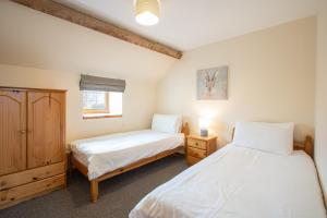a bedroom with two beds and a cabinet and a window at Yr Wyddfa Cottage Anglesey in Llanfairpwllgwyngyll