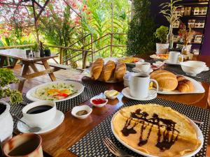 a table with plates of food and cups of coffee and croissants at Atmaland Resort in Kep