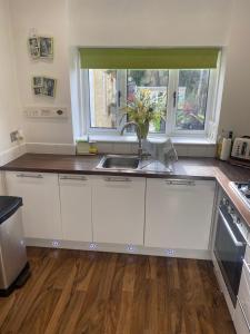 a kitchen with white cabinets and a sink and a window at Large Home, Close to BHX, NEC, JLR, 4 Double beds! in Birmingham