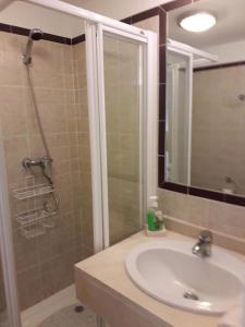 een badkamer met een wastafel en een douche met een spiegel bij Duquesa Fairways, a spacious apartment with fabulous views and facilities in Manilva