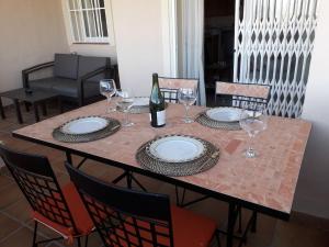 a table with a bottle of wine and glasses on it at Duquesa Fairways, a spacious apartment with fabulous views and facilities in Manilva