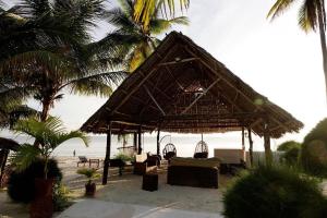 een hut op het strand met stoelen en palmbomen bij Moonshine Uroa Boutique Hotel in Uroa