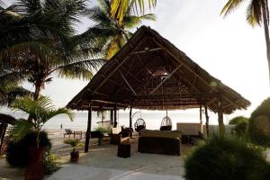 a hut on the beach with chairs and palm trees at Moonshine Uroa Boutique Hotel in Uroa