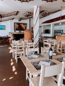 a restaurant with white tables and white chairs and a room at Hotel HS Milfontes Beach - Duna Parque Group in Vila Nova de Milfontes