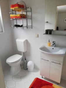 a white bathroom with a toilet and a sink at Ferienwohnung Tensfeldt in Lübben