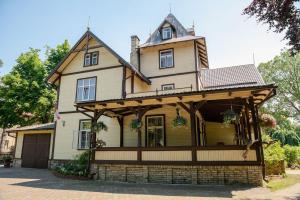 Cette maison ancienne est entourée d'une terrasse couverte. dans l'établissement Villa Magonīte, à Ventspils