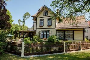 uma casa velha com uma cerca em frente em Villa Magonīte em Ventspils