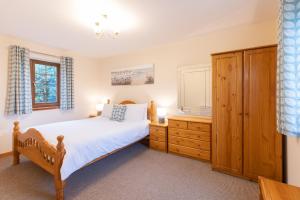 a bedroom with a bed and a dresser and a window at Crib Goch Cottage in Llanfairpwllgwyngyll