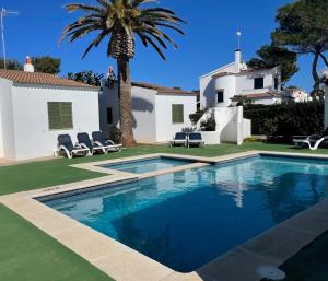 una piscina frente a una casa con palmeras en Villa Angelina 3 hab., en Cala Blanca