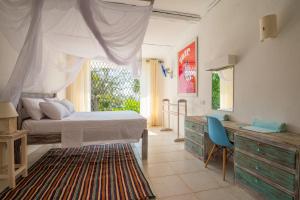1 dormitorio con cama, escritorio y ventana en Flamboyant Diani Beach en Diani Beach