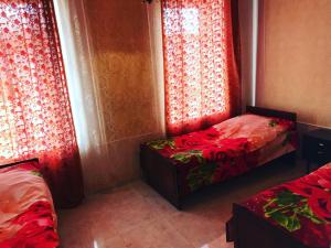 two beds in a room with red curtains at Hayq Guest House in Goris