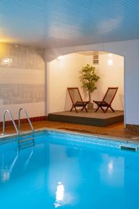 a pool with two chairs and a tree in a room at Cliff House Holiday Cottages in Ebberston