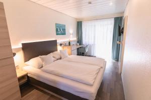 a bedroom with a white bed and a desk at Hotel Christine in Radolfzell am Bodensee +39 photos