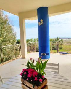 a porch with a blue column and flowers on a table at Casa Serra in Porto Palo