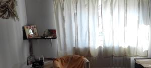 Habitación con una ventana con cortinas blancas y una silla en Pensiunea Ramona, en Viscri