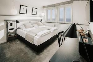 a bedroom with a bed and a desk and windows at Villa Breeksee in Norderney