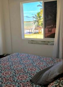 1 Schlafzimmer mit einem Fenster mit Blick auf den Strand in der Unterkunft Chalé Paraíso -Maracajaú 4- Casa 38 - Beira-mar in Maxaranguape