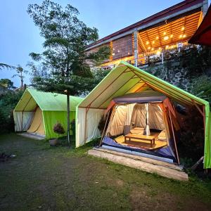 two tents in front of a building at night at Bagas Luxury Camp in Kejajar