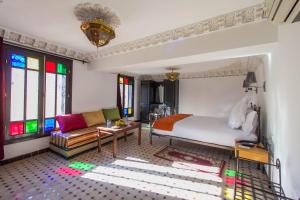 a bedroom with a bed and a couch and stained glass windows at Riad Fes Bab Rcif Sid Aowad & spa in Fès