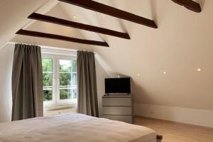a bedroom with a bed and a tv and a window at Nordseehaus Muschel in Dornum