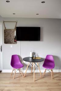 a table and two purple chairs in a room at Modern Luxury 1 bed apartment with parking near Stansted Airport in Stansted Mountfitchet