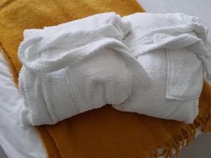 a pile of white towels on top of a bed at Petite Anchorage in Christchurch