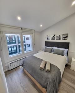 um quarto com uma cama grande e 2 janelas em Ático Merced. Tranquilo y bien situado em La Coruña