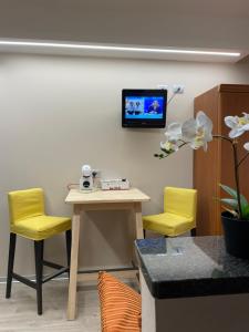 a room with a table and two chairs and a tv on the wall at Hotel & Apartments Rinaldo in Borgomanero