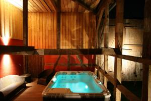 une baignoire jacuzzi dans une chambre avec des murs en bois dans l'établissement Les Authentics - Le Domaine d'Autrefois & Spa, à Bolsenheim