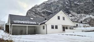 uma casa branca na neve com uma montanha em Cheerful 4-bedroom home with fireplace, 1,5km from Flåm center em Aurland