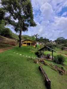 a yard with a tree and a house in the background at Espaço inteiro: Casa de campo nas montanhas in Domingos Martins