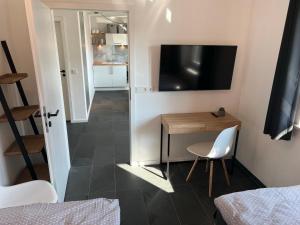 a room with a table and a television on a wall at Schöne Designer-Wohnung im Mangfalltal in Bruckmühl