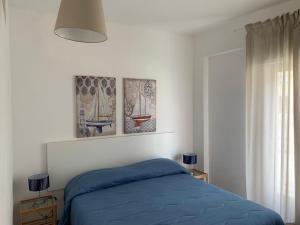 a bedroom with a blue bed with three pictures on the wall at Appartamento Mare Blu in Sciacca