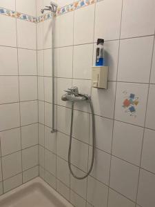 y baño de azulejos blancos con ducha y manguera. en Geräumige Wohnung im Schweizer Vekehrspunkt, en Hunzenschwil