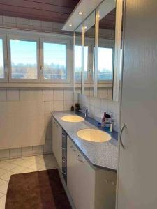 a bathroom with two sinks and two mirrors at Geräumige Wohnung im Schweizer Vekehrspunkt in Hunzenschwil