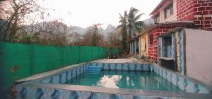 GhātgharWeekend Villa at Nature's Lap (Malshej Ghat)的一座带绿色围栏的房屋旁的游泳池
